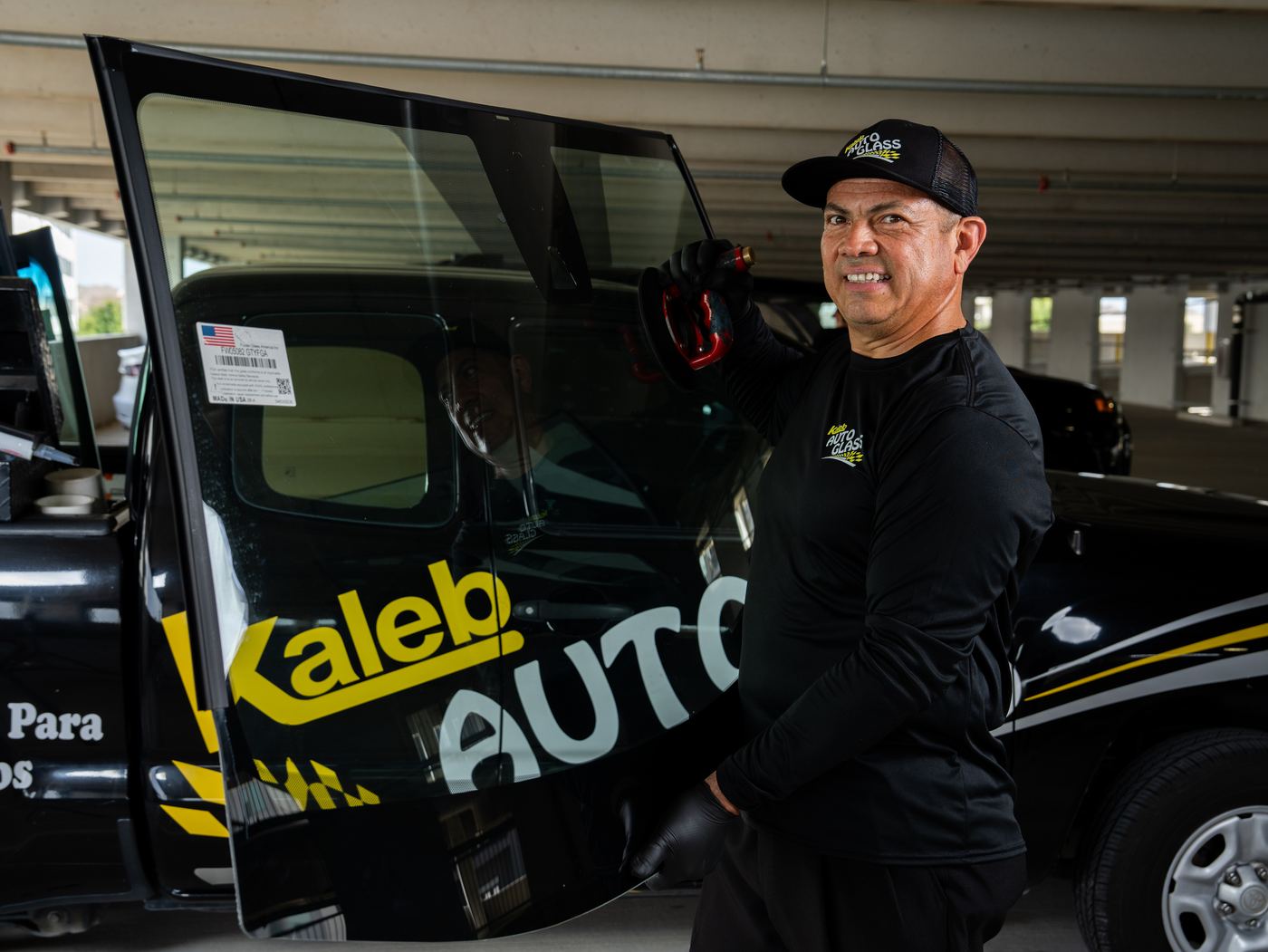 KAG technician carrying a new windshield beside the KAG truck